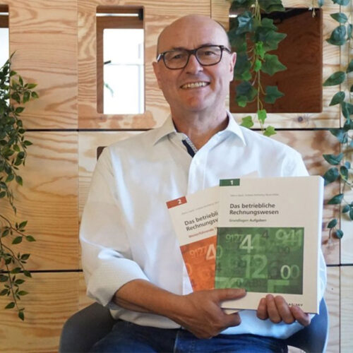 Markus Speck zeigt die beiden Bände von "Das betriebliche Rechnungswesen"